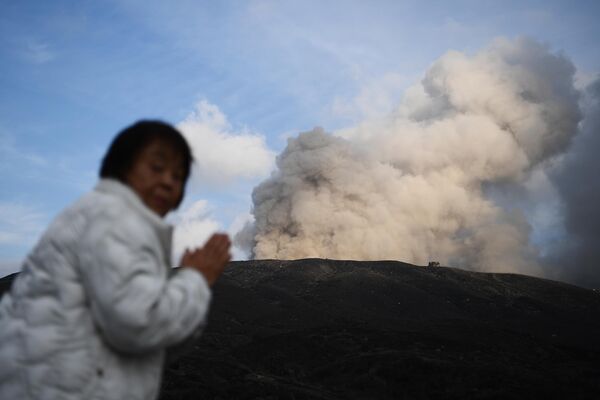 Женщина стоит возле действующего вулкана в городе Асо в префектуре Кумамото