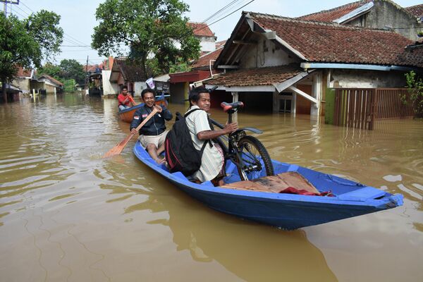 Жители добираются на лодке через затопленную дорогу в Дайехколоте, Индонезия