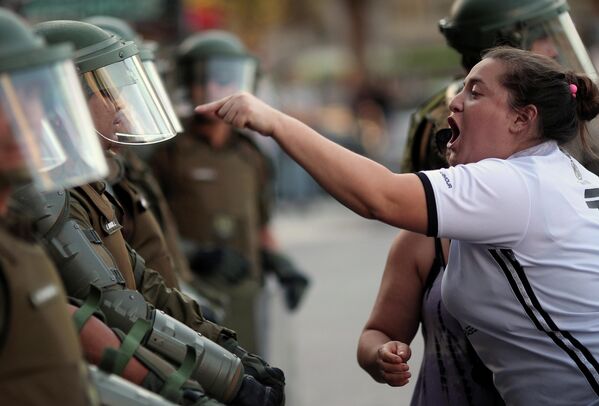 Женщина спорит с сотрудником ОМОНа во время протестов в Чили