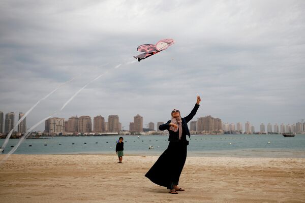 Девушка с воздушным змеем на пляже в Дохе, Катар