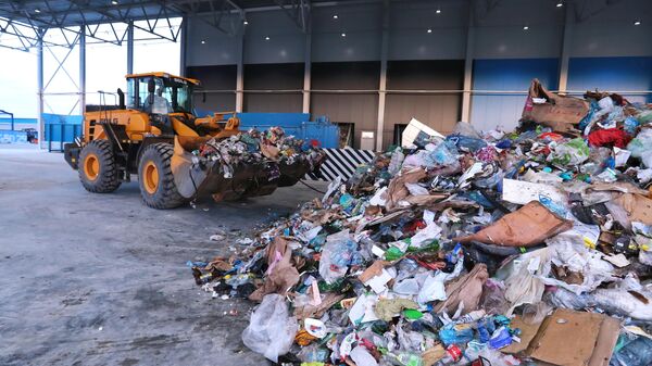 Экскаватор-погрузчик на территории комплекса по переработке отходов Восток в Московской области