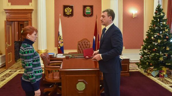 Губернатор Амурской области Василий Орлов вручает медаль За спасение погибавших Марине Пачикиной