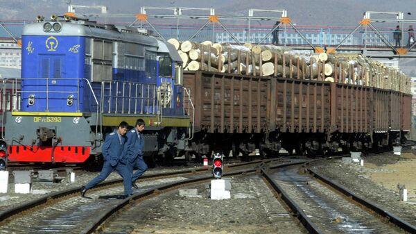 Железнодорожные рабочие возле поезда, перевозящего древесину, импортируемую из России, на железнодорожной станции в Суйфэньхэ, Китай