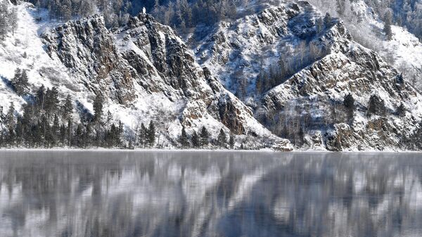 Покрытый снегом крутой таежный берег реки Енисей напротив города Дивногорска Красноярского края