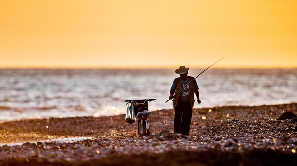 Рыбак на закате на набережной 