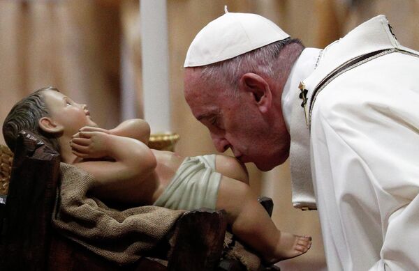 Папа Франциск целует статую младенца Иисуса во время рождественской мессы в Ватикане