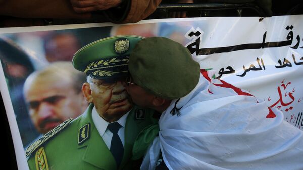 Женщина целует изображение генерал-лейтенанта Ахмеда Гаеда Салаха во время его похорон в Алжире