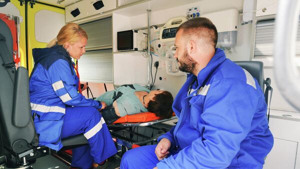 Врачи бригады скорой медицинской помощи оказывают первую помощь пациенту в салоне реанимобиля
