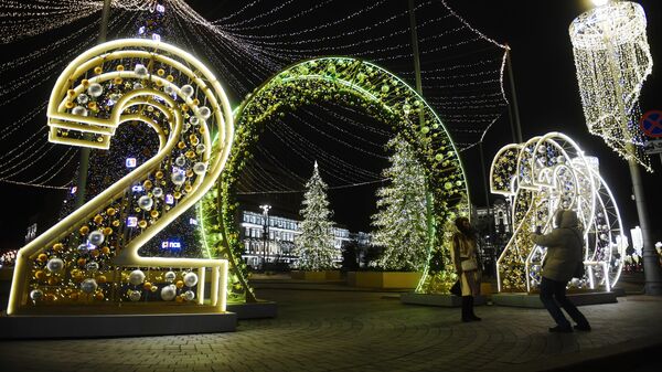 Прохожие фотографируются у световой иллюминации на Лубянской площади в Москве