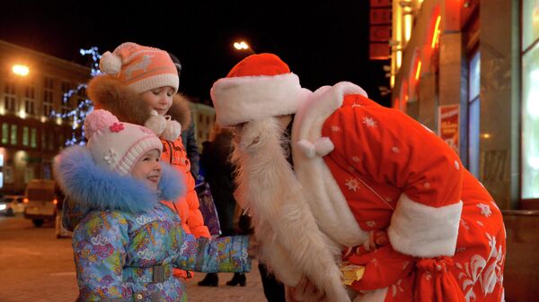 Человек в костюме Деда Мороза поздравляет детей с наступающим Новым годом на проспекте Независимости в Минске