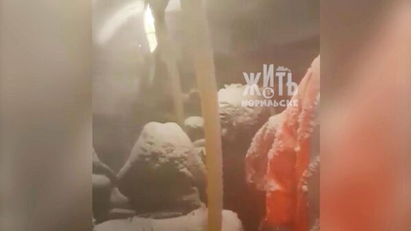 Стоп-кадр видео, на котором показан салон автобуса с пассажирами припорошенными снегом в Норильске