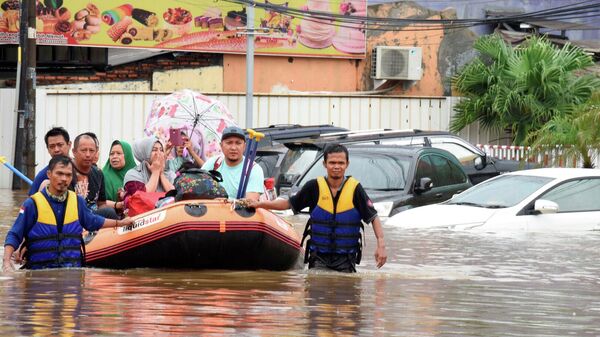Спасатели  эвакуируют местных жителей  во время наводнения после сильного дождя  недалеко от Джакарты, Индонезия. 1 января 2020 