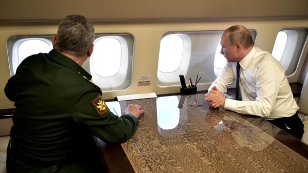 Президент РФ Владимир Путин и министр обороны РФ Сергей Шойгу на борту президентского самолета во время полета в Сирию