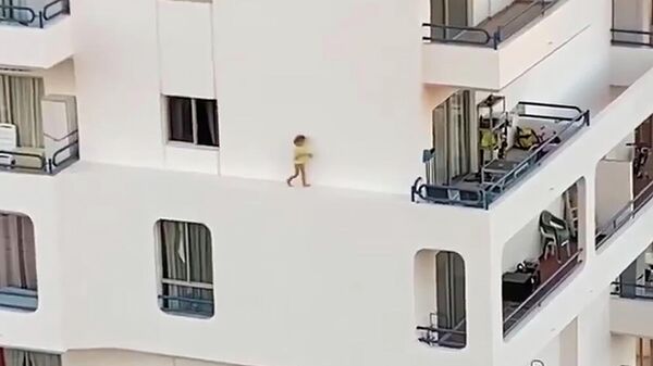 Стоп-кадр видео, на котором ребенок бежит по выступу здания на четвертом этаже