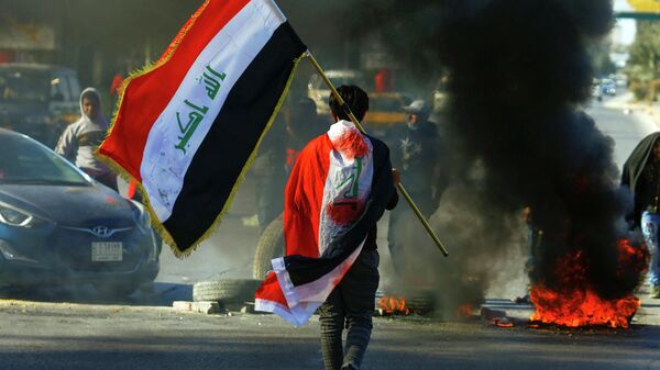 Мужчина с иракским флагом во время продолжающихся демонстраций на улицах Ирака. 12 января 2019