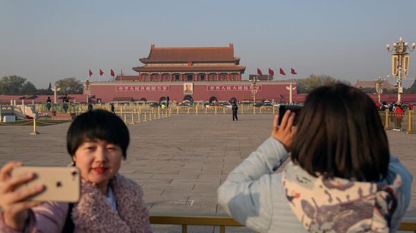 Девушки фотографируются на площади Тяньаньмэнь в Пекине