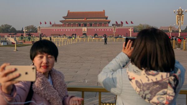 Девушки фотографируются на площади Тяньаньмэнь в Пекине