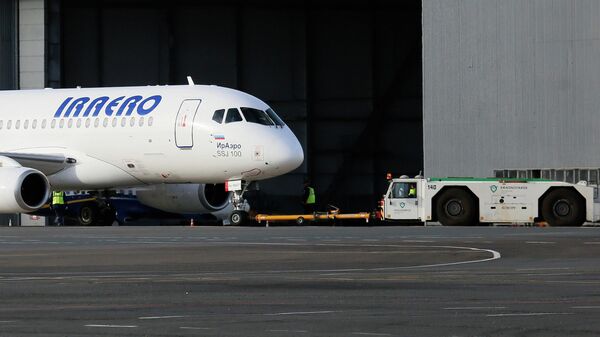 Тягач буксирует пассажирский самолет Сухой Суперджет-100 авиакомпании ИрАэро