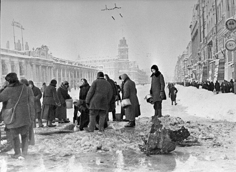 Жители блокадного Ленинграда набирают воду, появившуюся после артобстрела в пробоинах в асфальте