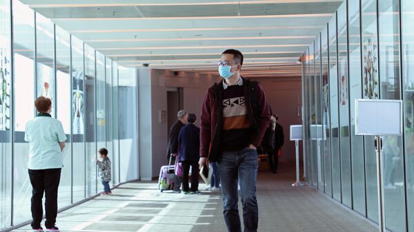 Пассажир в маске, прибывший из китайского Ханчжоу, в аэропорту Чанги, Сингапур