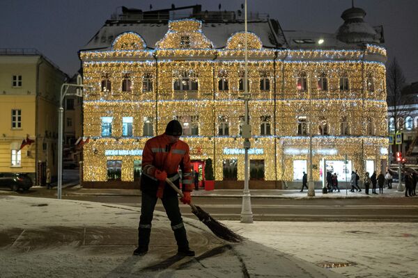 Сотрудник коммунальной службы подметает тротуар на улице Пречистенка в Москве