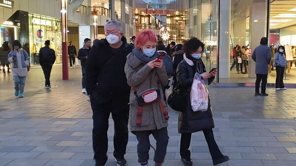 Прохожие в защитных масках на одной из улиц в Пекине