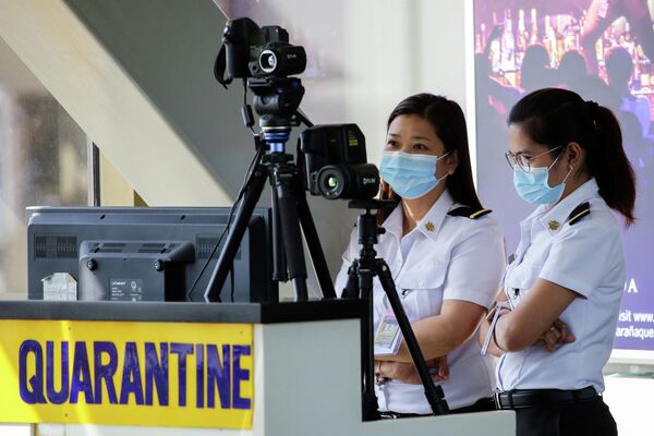 Сотрудники аэропорта следят за тепловым сканером в международном аэропорту Манила имени Ниноя Акино