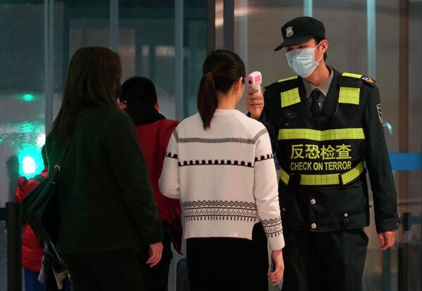 Сотрудник аэропорта проверяет пассажиров, покидающих международный аэропорт Ухань Тяньхэ в Ухане