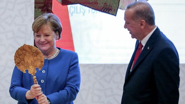 Канцлер Германии Ангела Меркель получает подарок от президента Турции Тайипа Эрдогана во время официальной церемонии открытия нового кампуса Турецко-германского университета в Стамбуле, Турция. 24 января 2020  