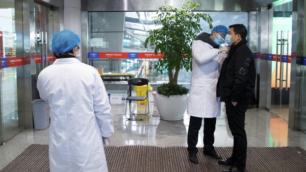 Медицинские работники измеряет температуру тела мужчины в зале вылета аэропорта в китайском городе Чанша