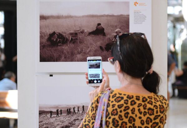Посетительница фотографирует на мобильный телефон одну из фотографий на выставке работ победителей Международного конкурса фотожурналистики имени Андрея Стенина