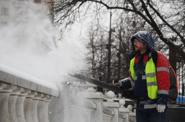 Сотрудник коммунальной службы чистит парапет у Александровского сада в Москве от снега