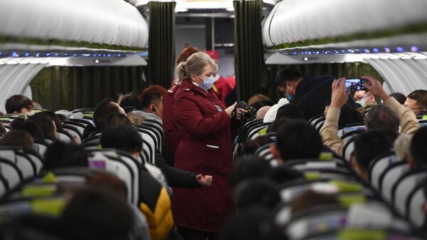 Сотрудники Роспотребназдора обследуют при помощи тепловизора пассажиров рейса авиакомпании S7, прибывшего из Пекина, в аэропорту Толмачево (Новосибирск)