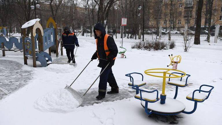 Сотрудники коммунальной службы чистят детскую площадку от снега в Москве