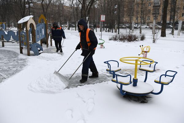 Сотрудники коммунальной службы чистят детскую площадку от снега в Москве