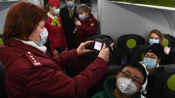Сотрудники Роспотребназдора обследуют при помощи тепловизора пассажиров рейса авиакомпании S7, прибывшего из Пекина, в аэропорту Толмачево