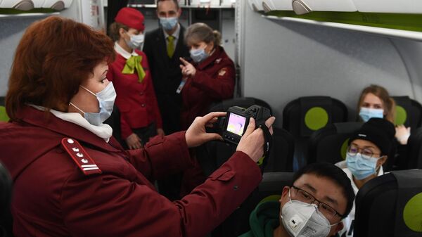 Сотрудники Роспотребназдора обследуют при помощи тепловизора пассажиров рейса авиакомпании S7, прибывшего из Пекина, в аэропорту Толмачево