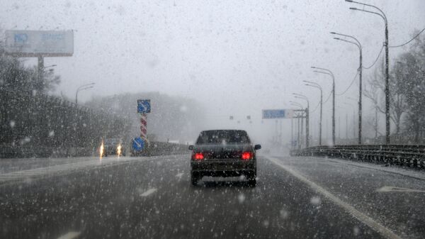 Автомобиль едет по Минскому шоссе во время снегопада в Москве