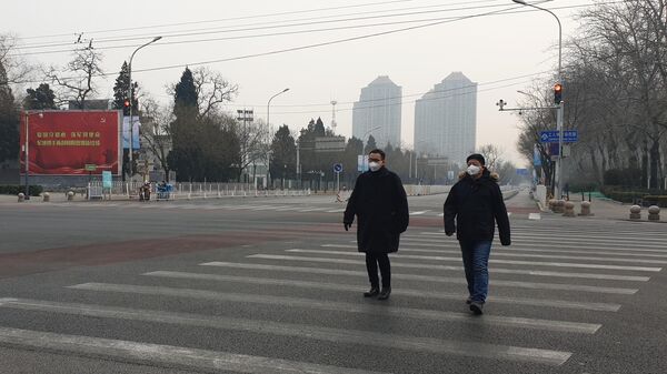 Мужчины в медицинских масках переходят улицу в Пекине