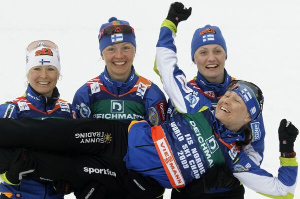 Пирьо Муранен (слева), Вирпи Куйтунен (в центре) и Ритта-Лиза Ропонен держат Айно-Кайсу Сааринен после победы в эстафете на ЧМ по лыжным видам спорта