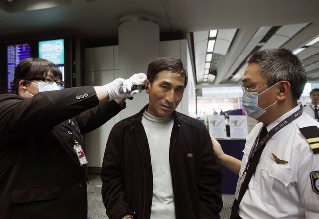 Сотрудники аэропорта Гонконга проверяют пассажиров, прибывших из Мексики
