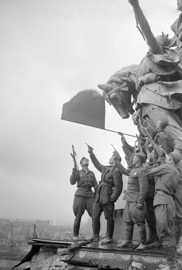 Советские воины салютуют, стоя на крыше рейхстага. 1945 год.
