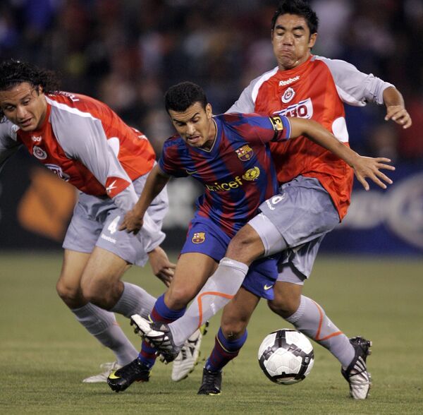 Нападающий Барселоны Педро Родригес (в центре) в борьбе за мяч с футболистами мексиканского Чиваса