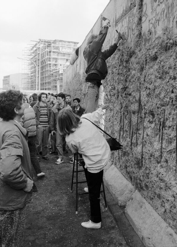 Житель Берлина отбивает кусок бетона от Берлинской стены