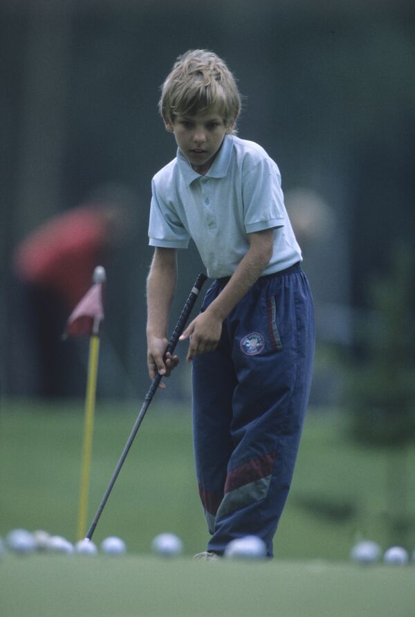 Мальчик учится играть в гольф. Архив