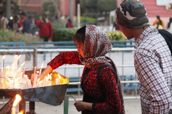 Прихожанка ставит свечку у католического собора в Дели