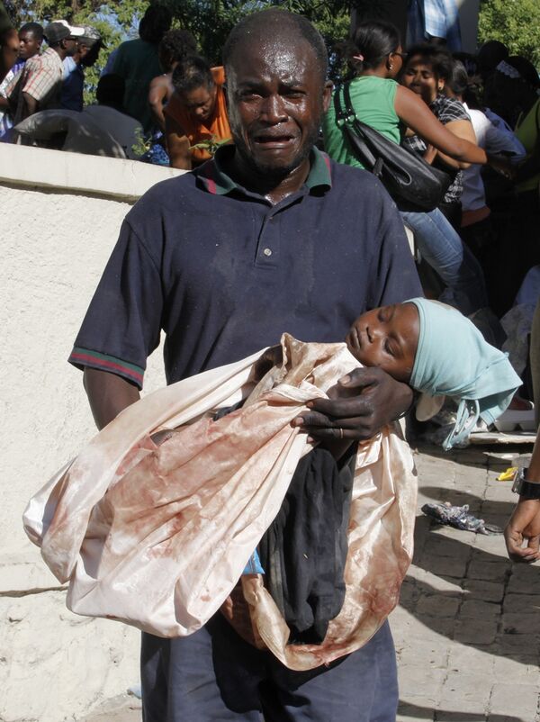 Мужчина несет тело своей мертвой дочери, погибшей во время землетрясения на Гаити