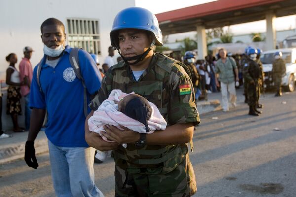 Миротворец ООН из Боливии несет гаитянского ребенка во время проведения гуманитарной операции помощи пострадавшим от землетрясения на Гаити. 
