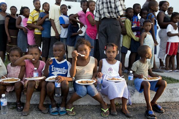 Дети едят пищу, розданную им в рамках гуманитарной операции на Гаити