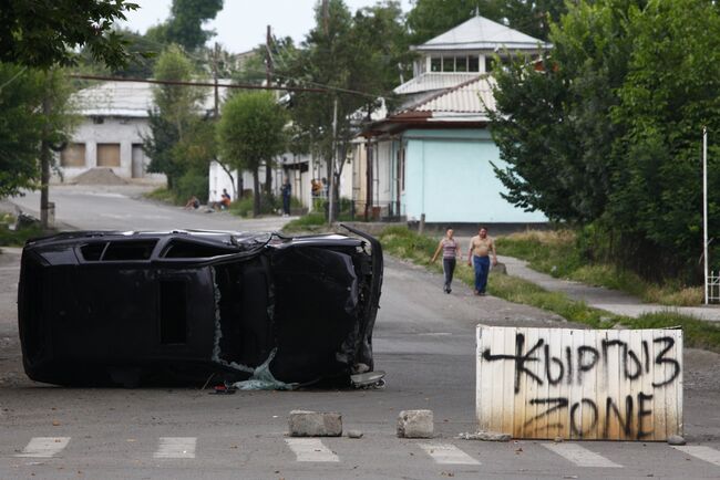 Перевернутый автомобиль и надпись Кыргыз зона на улице города Ош. Архив